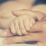 Hand holding newborn baby
